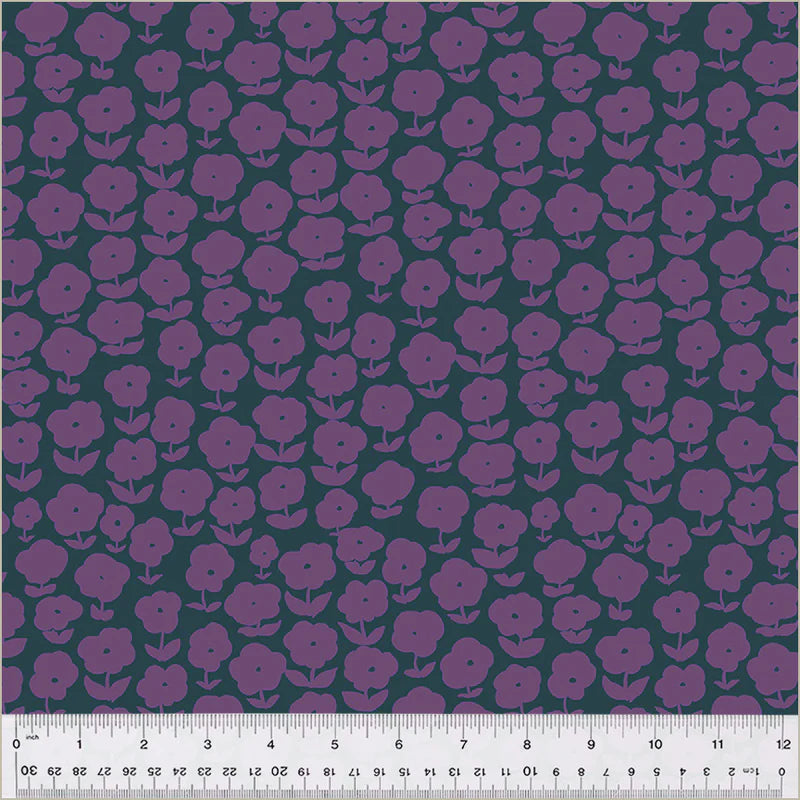 Patterned fabric with purple flowers on a green background, measured with a ruler at the bottom.